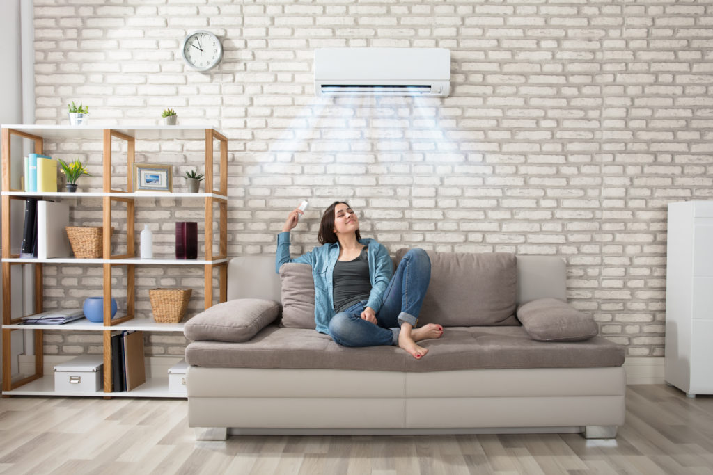 Lady resting on couch cooling under Air conditioning system